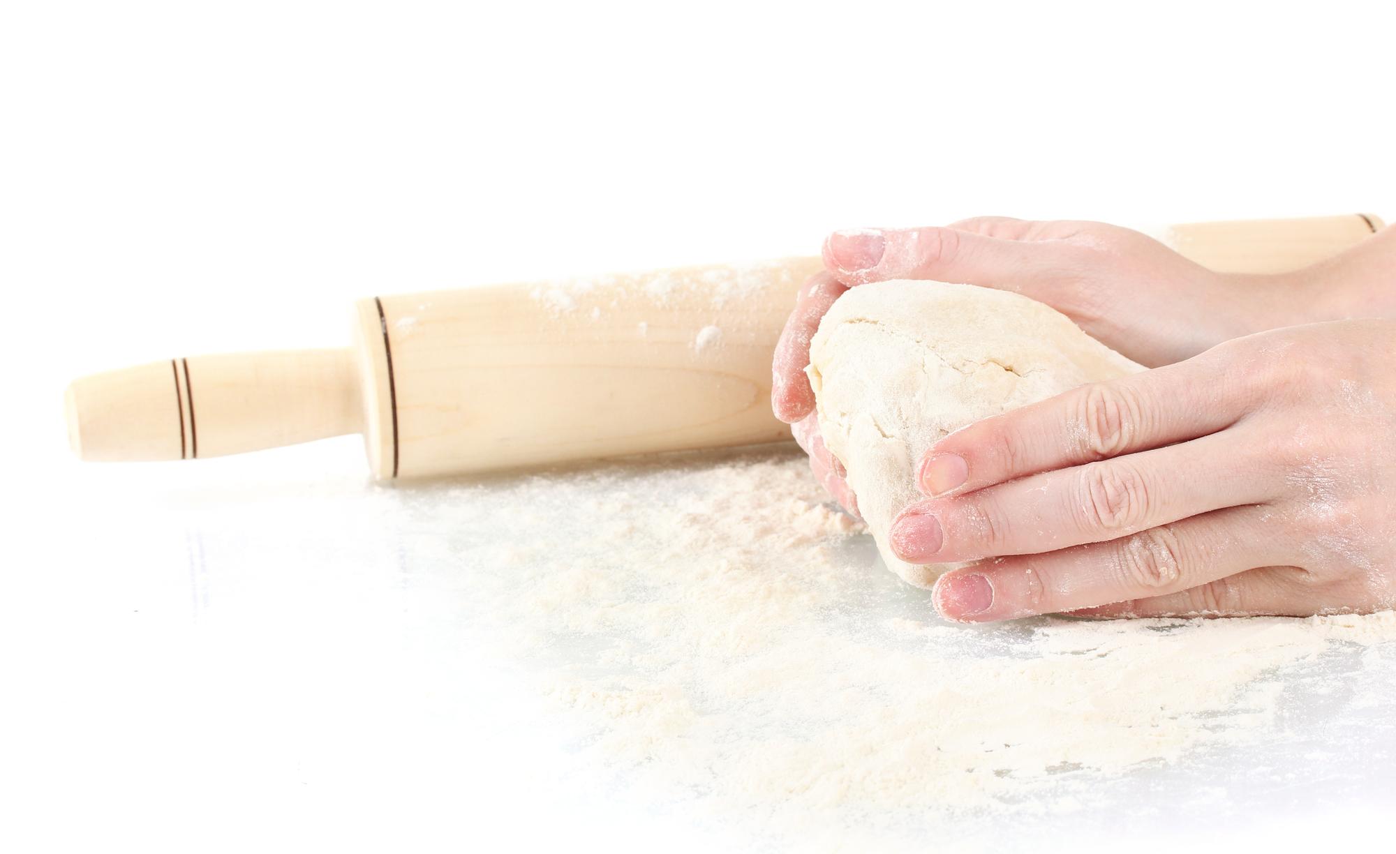 Student rolling pasta dough on wooden board